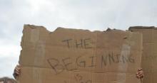 Photo of woman holding a sign reading, "The Beginning is Near"