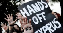 Image of people holding a sign that reads, "Hands off Cyprus"