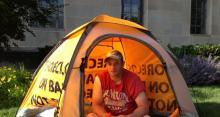 Photo of man sitting in a yellow tent.