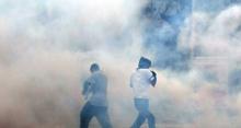 Photo: two people being engulfed by tear gas.