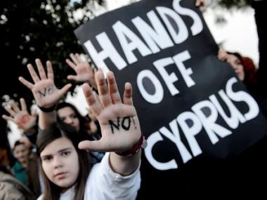 Image of people holding a sign that reads, "Hands off Cyprus"