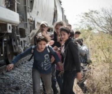 Child migrants from central america climb on a train heading north