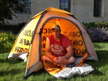 Photo of man sitting in a yellow tent.