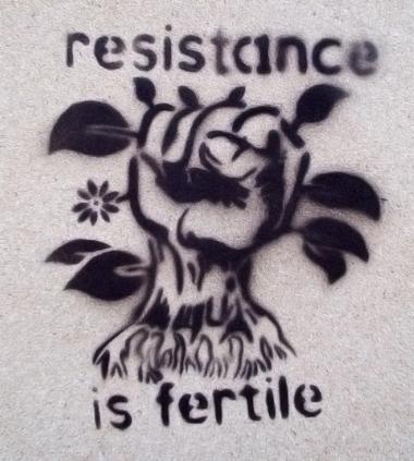 Photo of stencil illustration on wall that reads, "Resistance is fertile."