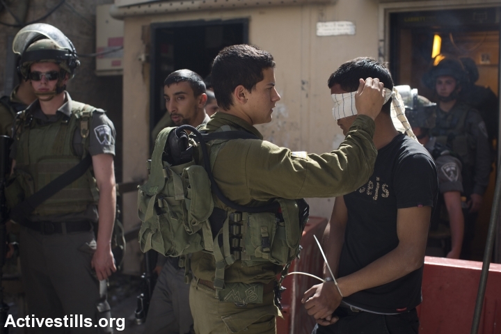 Israeli soldiers blindfold and arrest a young Palestinian man in Hebron. (photo: Activestills.org)